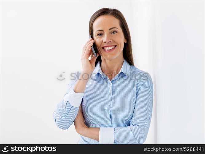 business, communication and people concept - happy businesswoman calling on smartphone at office. businesswoman calling on smartphone at office