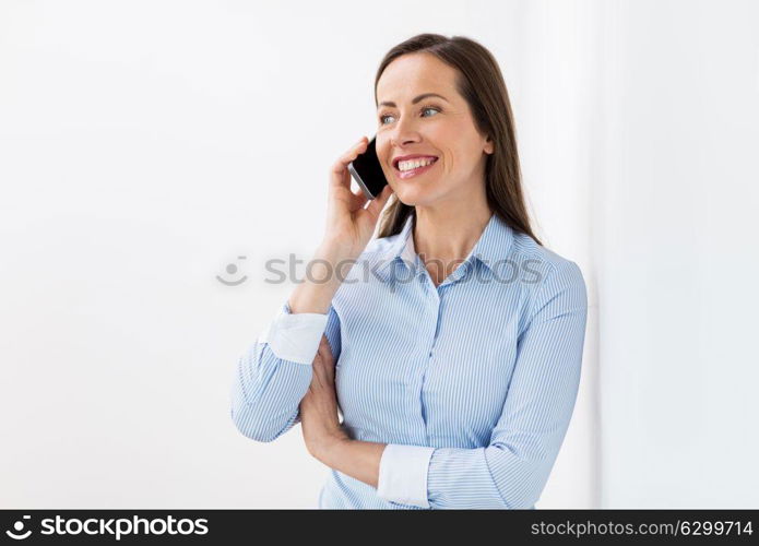 business, communication and people concept - happy businesswoman calling on smartphone at office. businesswoman calling on smartphone at office