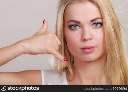 Business communication. Attractive businesswoman making call me gesture. blonde girl with phone hand sign on gray