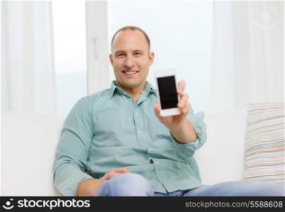 business, communication, home and modern technology concept - smiling man with smartphone at home