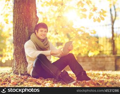 business, communication, modern technology and leisure concept - man with tablet pc in autumn park
