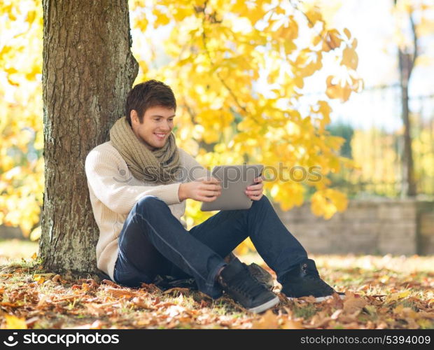 business, communication, modern technology and leisure concept - man with tablet pc in autumn park