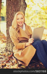 business, communication, modern technology and leisure concept - woman with tablet pc in autumn park