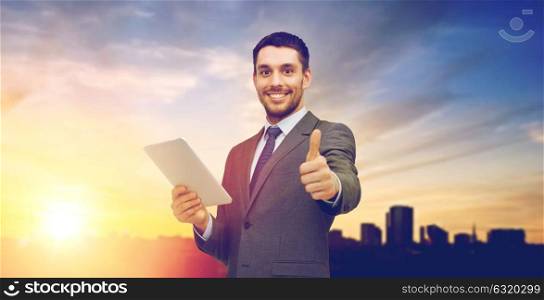 business, communication, modern technology and office concept - smiling businessman with tablet pc computer showing thumbs up over city background. smiling businessman with tablet pc computer