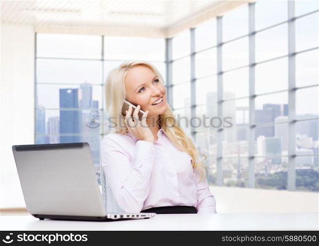 business, communication, people and technology concept - smiling businesswoman or secretary with laptop computer calling on smartphone over office room with city view window background