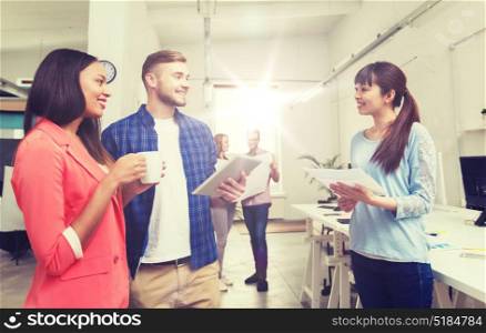 business, communication, startup and people concept - happy multiracial creative team or students with tablet pc and papers on coffee break talking at office. creative team with tablet pc and papers at office