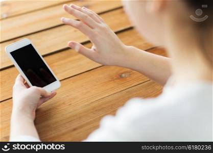 business, communication, technology and internet concept - close up of woman with smartphone waving hand