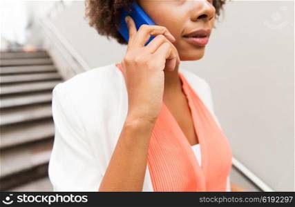 business, communication, technology and people concept - close up of african woman calling on smartphone walking downstairs to city subway