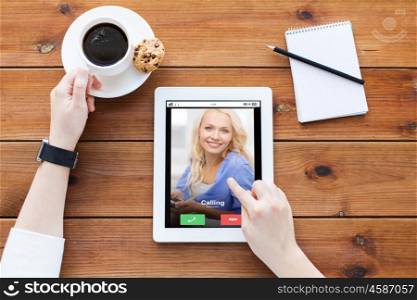 business, communication, technology and people concept - close up of woman with incoming call on tablet pc computer screen, notebook and coffee on wooden table