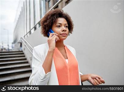 business, communication, technology and people concept - young african american businesswoman calling on smartphone going down stairs into city underpass