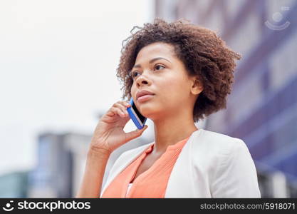 business, communication, technology and people concept - young african american businesswoman calling on smartphone in city