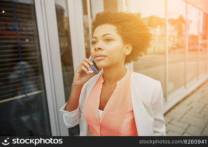 business, communication, technology and people concept - young african american businesswoman calling on smartphone in city