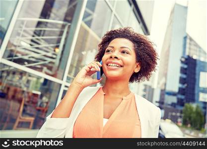 business, communication, technology and people concept - young smiling african american businesswoman calling on smartphone in city