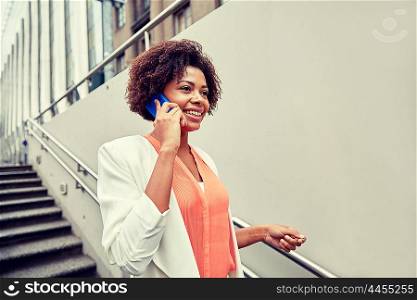 business, communication, technology and people concept - young smiling african american businesswoman calling on smartphone going down stairs into city underpass