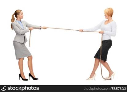 business competition concept - two smiling businesswomen pulling rope