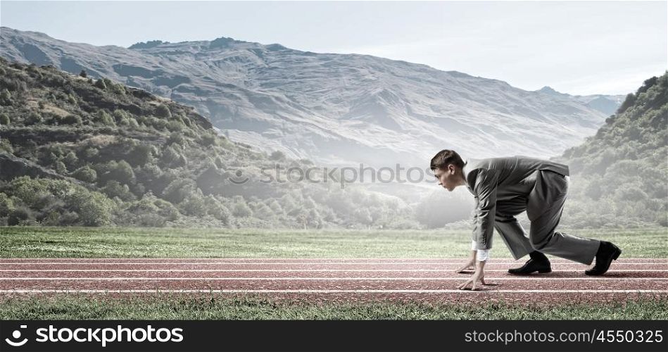 Business competition. Side view of young businessman in start position on track