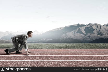 Business competition. Side view of young businessman in start position on track