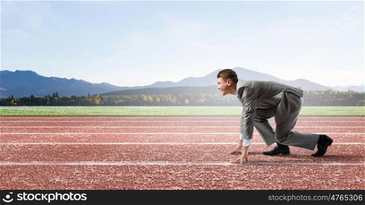 Business competition. Side view of young businessman in start position on track