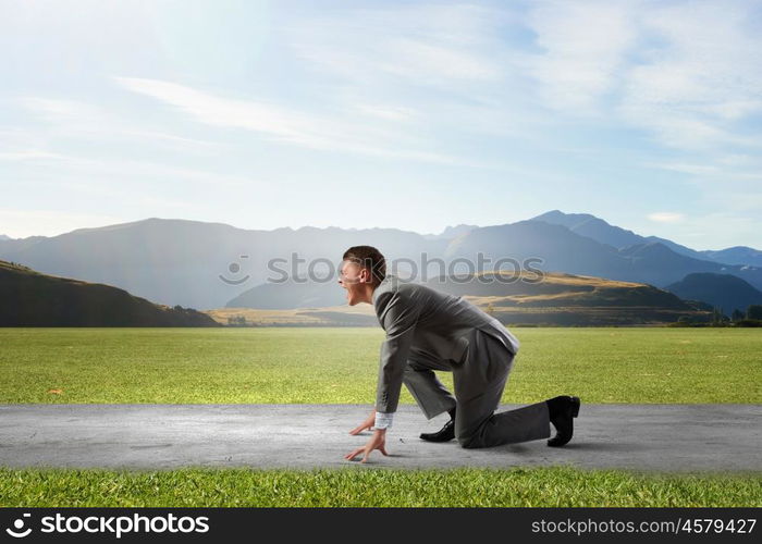 Business competition. Side view of young businessman in start position ready to run