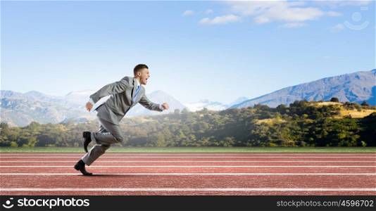 Business competition. Young businessman in suit running on track