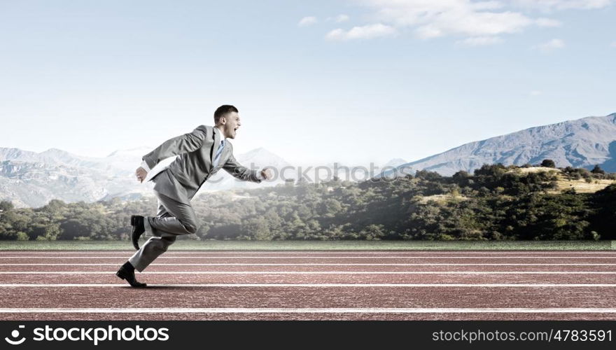 Business competition. Young businessman in suit running on track