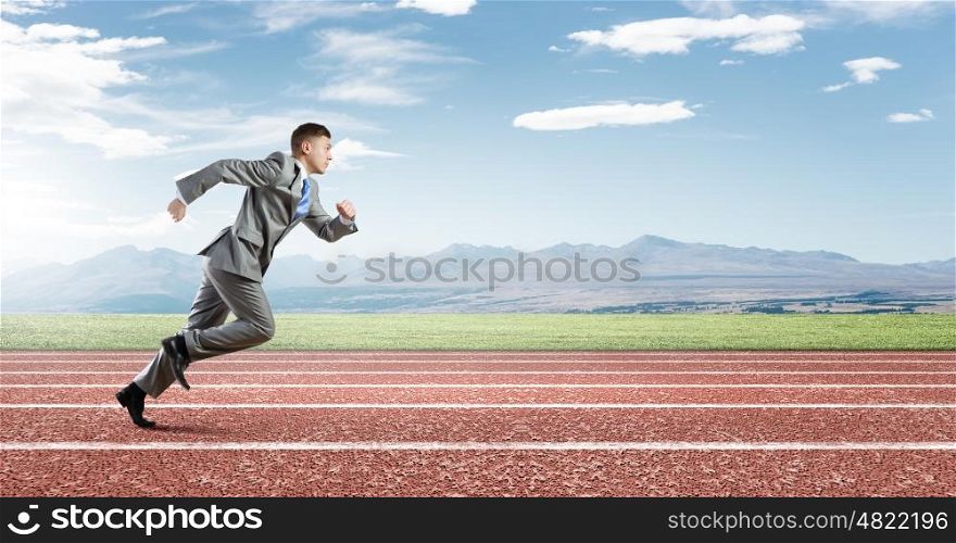 Business competition. Young businessman in suit running on track