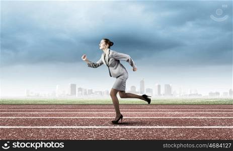 Business competition. Young businesswoman in suit running on track