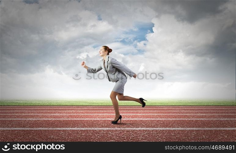 Business competition. Young businesswoman in suit running on track