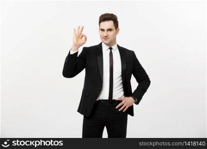 Business Concept: A handsome man in smart suit isolated on gray background showing ok sign. Business Concept: A handsome man in smart suit isolated on gray background showing ok sign.