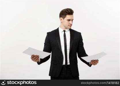 Business Concept: Attentive handsome businessman working comparing paper report. Isolated over white grey background. Business Concept: Attentive handsome businessman working comparing paper report. Isolated over white grey background.