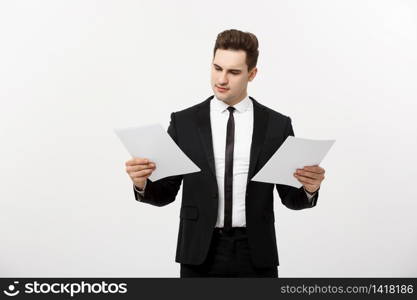 Business Concept: Attentive handsome businessman working comparing paper report. Isolated over white grey background. Business Concept: Attentive handsome businessman working comparing paper report. Isolated over white grey background.