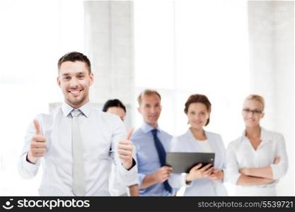 business concept - attractive businessman in office showign thumbs up