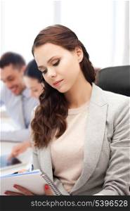 business concept - attractive businesswoman taking notes in office