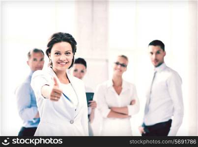 business concept - attractive businesswoman with team in office showing thumbs up