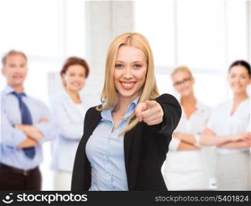business concept - attractive young businesswoman pointing at you in office