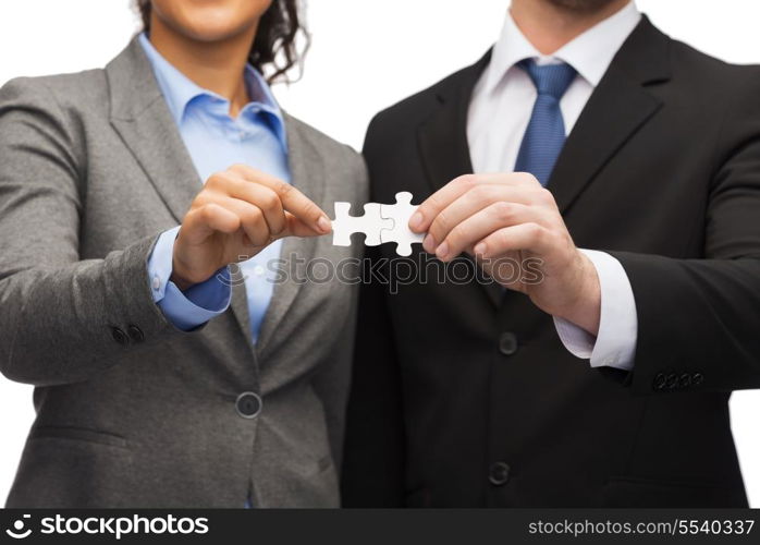 business concept - businessman and businesswoman holding puzzle pieces in office