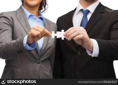 business concept - businessman and businesswoman holding puzzle pieces in office