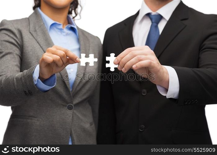 business concept - businessman and businesswoman trying to connect puzzle pieces in office