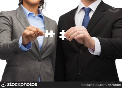 business concept - businessman and businesswoman trying to connect puzzle pieces in office