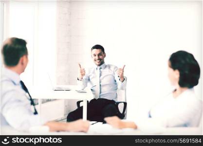 business concept - businessman showing thumbs up in office