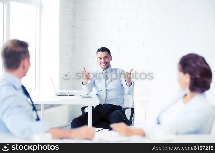 business concept - businessman showing thumbs up in office. businessman showing thumbs up in office