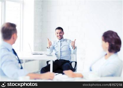 business concept - businessman showing thumbs up in office. businessman showing thumbs up in office
