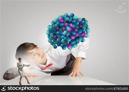 Business concept. Businesswoman looking at businesswoman miniature pulling bunch of balloons