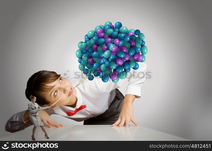 Business concept. Businesswoman looking at businesswoman miniature pulling bunch of balloons