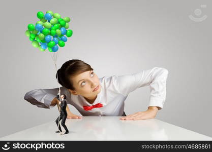 Business concept. Businesswoman looking from under the table at businessman miniature