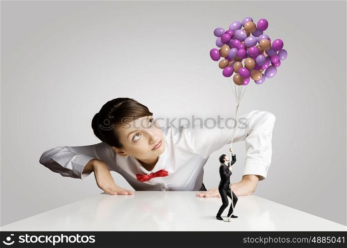 Business concept. Businesswoman looking from under the table at businessman miniature