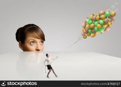 Business concept. Businesswoman looking from under the table at businesswoman miniature