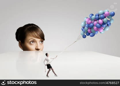 Business concept. Businesswoman looking from under the table at businesswoman miniature