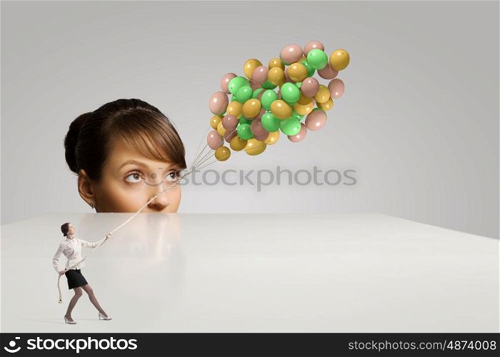 Business concept. Businesswoman looking from under the table at businesswoman miniature