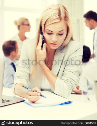 business concept - businesswoman talking on the phone and taking notes in office